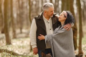 A happy senior couple embracing in a sunny forest, showcasing love and togetherness.